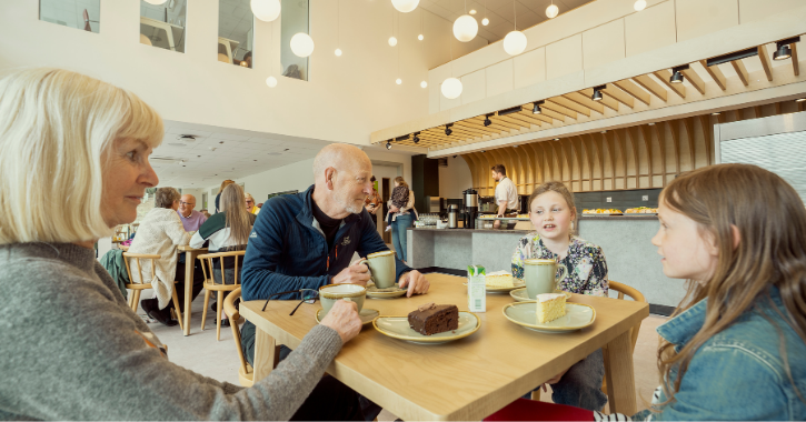 Family of two adults and two children enjoying food and drink in the cafe inside The Light, Durham.